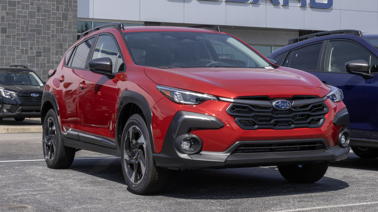 A red Subaru Crosstrek Limited AWD Compact SUV at a dealership.