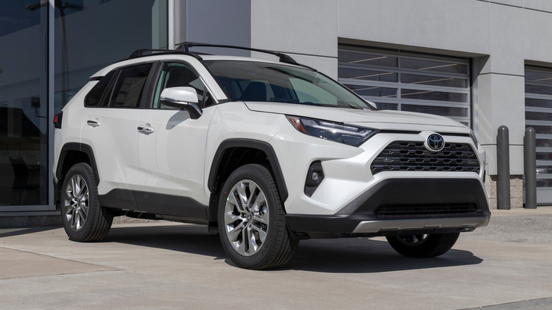 A white Toyota RAV4 on display outside of a dealership.
