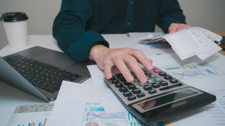Close up of businessman hand calculating budget with calculator.