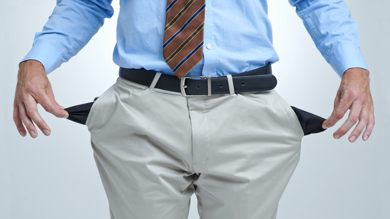 Man in dress clothes turns out pockets to show nothing inside.