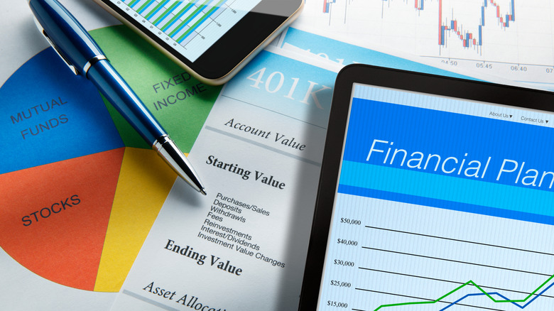 A high angle view of a digital tablet with a financial plan on its screen while it rests on top of a monthly account statement.