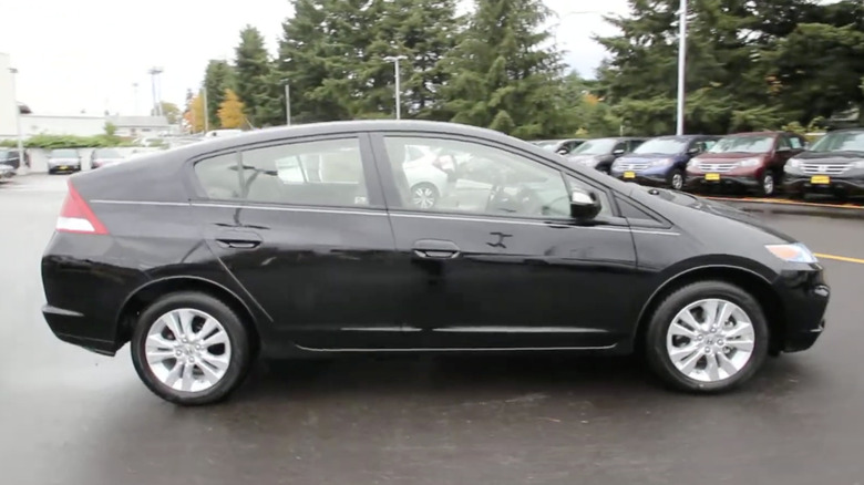A black 2014 Honda Insight parked outside of a dealership on a rainy day