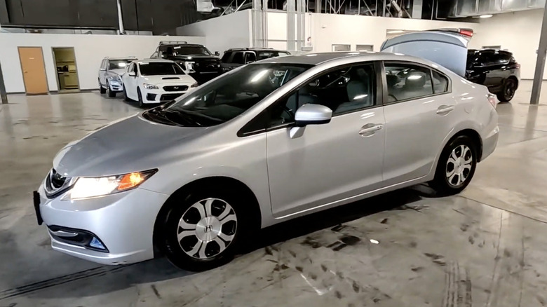 A silver 2015 Honda Civic Hybrid in a garage with its trunk open