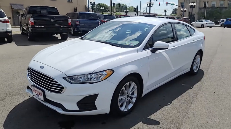 A white 2020 Ford Fusion Hybrid parked near a busy road on a sunny day