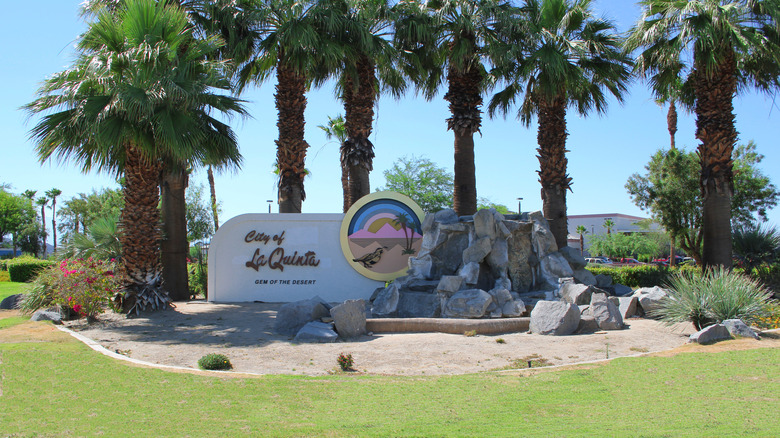 The welcome sign for La Quinta, California surrounded by palm trees.