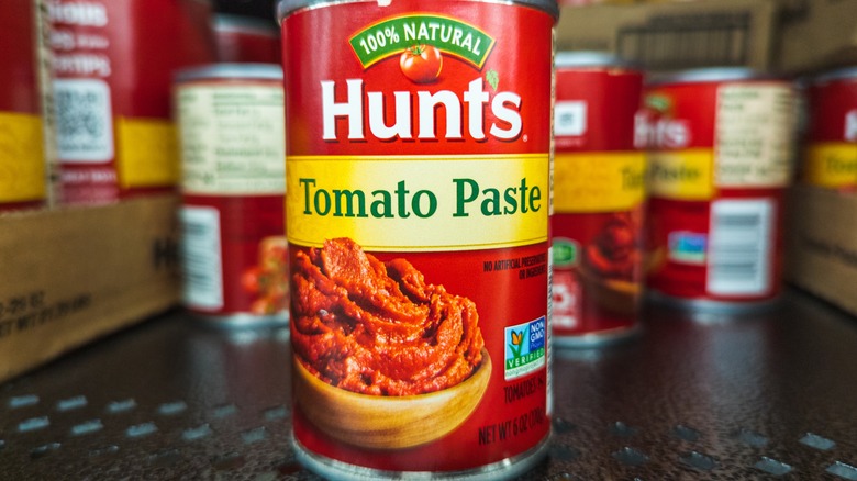 Close up of red can of Hunt's tomato paste with additional cans in the background