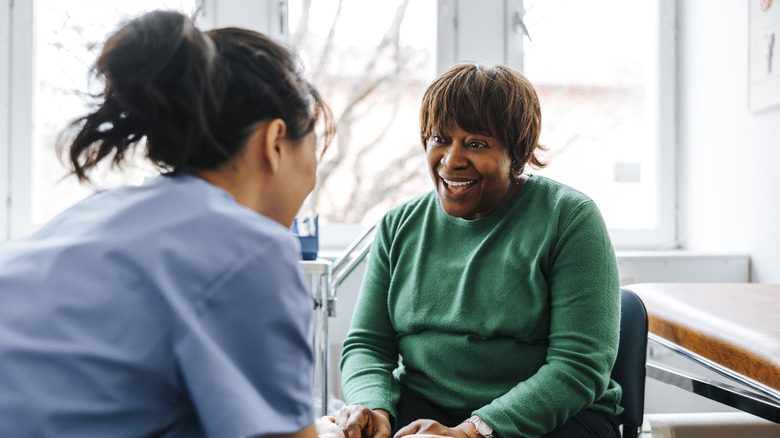 Young female nurse interacting with senior citizen patient in wheelchair.