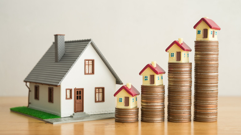 House on stack coin growth as chart on wooden table with white wall background.