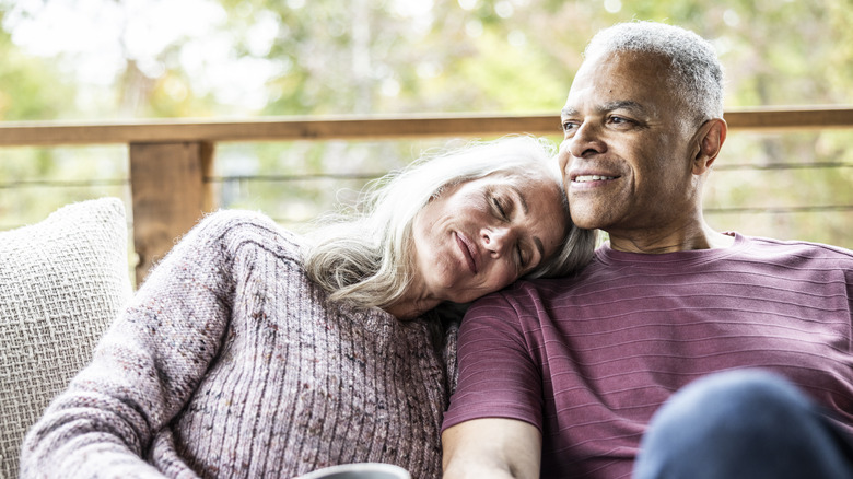 Senior couple having coffee and embracing on back porch of vacation home.
