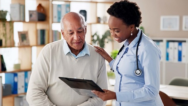 An older male patient looking over his chart with a doctor