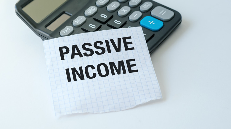 A calculator sits on a table with a piece of paper that says "Passive Income."