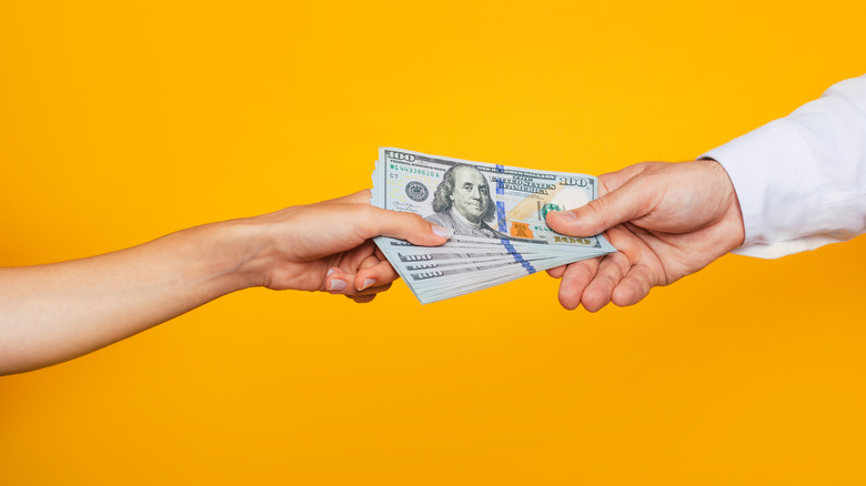 people passing $100 bills to one another