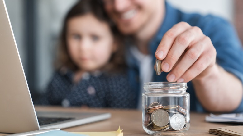 father and child saving coins in jar