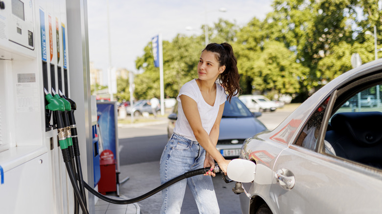 A millennial woman pumping gas
