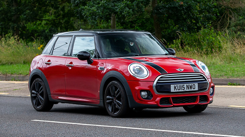 A red Mini Cooper car traveling on an English road.