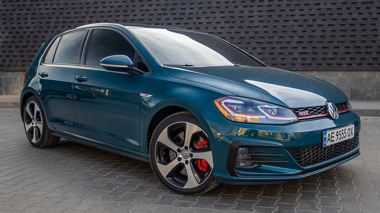 A green car Volkswagen Golf GTI on the street.