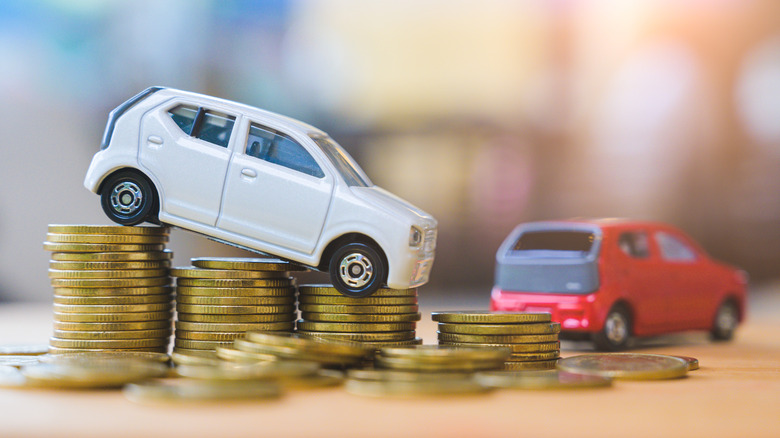 Toy cars sitting on and around a stack of coins.