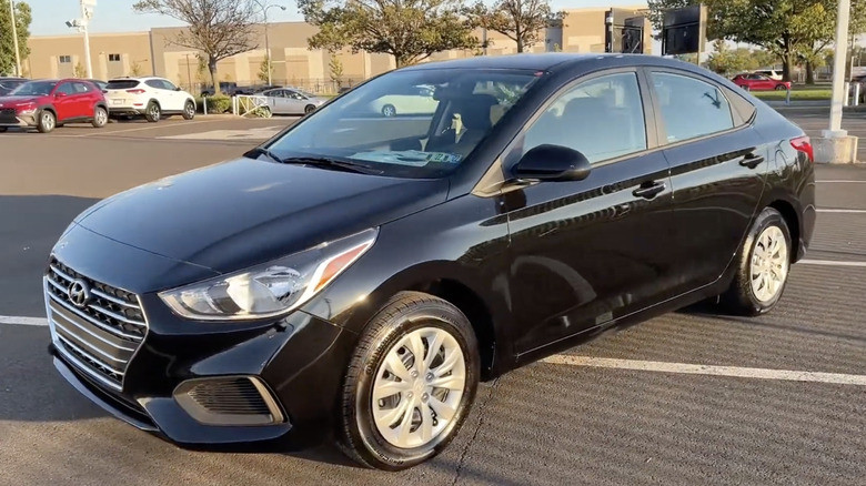 The sun setting on a black 2022 Hyundai Accent in a commercial parking lot