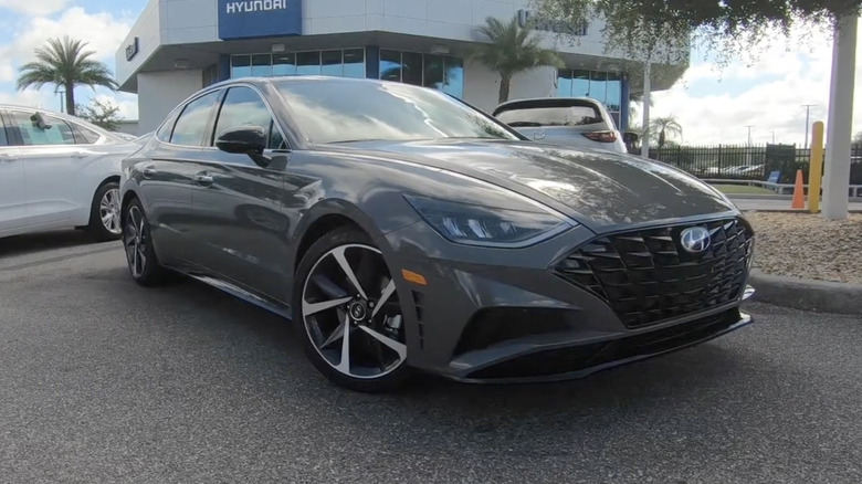 An offset view of a gray 2022 Hyundai Sonata SEL PLUS parked outside of a dealership