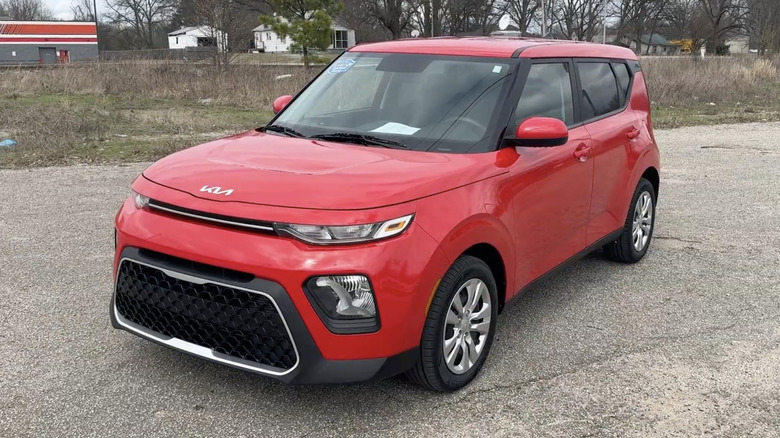 A red 2022 Kia Soul LX parked diagonally across a street on a cloudy day