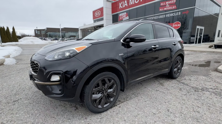 A black 2022 Kia Sportage EX-S parked in a Kia dealership's snowy parking lot