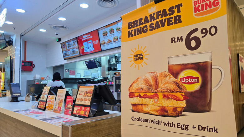 A Burger King counter showcasing breakfast promotion featuring Croissan'wich with egg and Lipton tea.