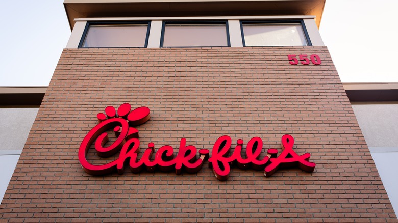 The logo sign of a Chick-fil-A on the restaurant facade, a popular American fast-food chain specializing in chicken sandwiches.