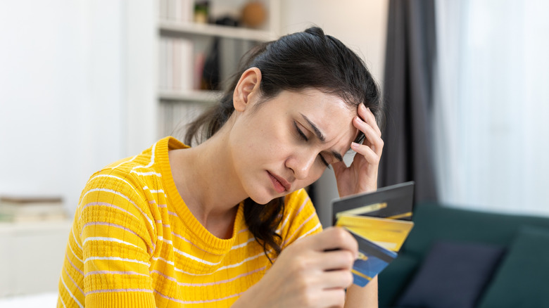 Frustrated woman holding multiple credit cards.