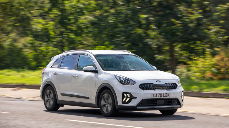 A 2021 white Kia Niro hybrid electric car driving on a British road