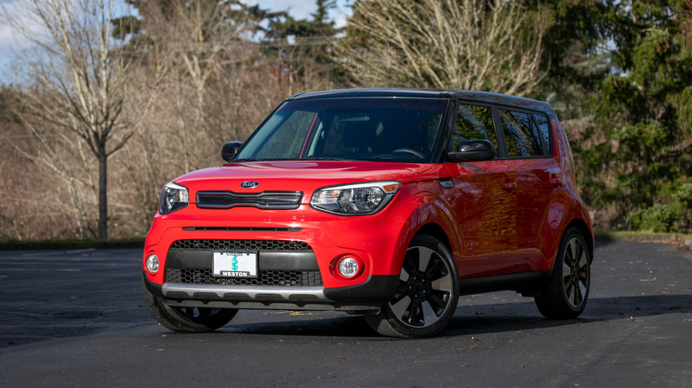 A red Kia Soul South Korean hatchback car parked outdoors in daylight.