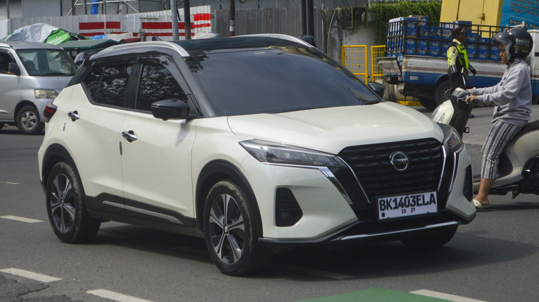 A white crossover 2021 Nissan Kicks driving on the streets.