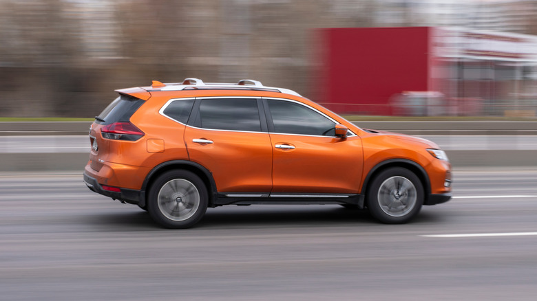 Orange Nissan Rogue car moving on the street.