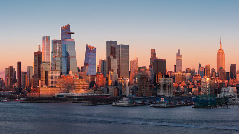 The New York City skyline with Hudson River Park and Manhattan skyscrapers at sunset.