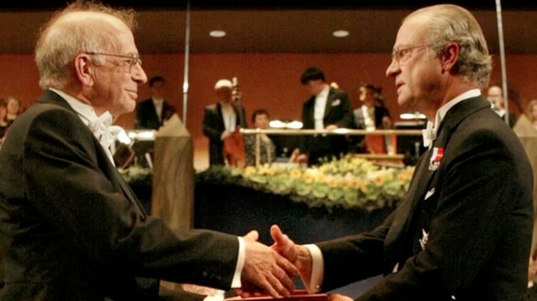 Daniel Kahneman and Amos Tversky wearing tuxedos and shaking hands