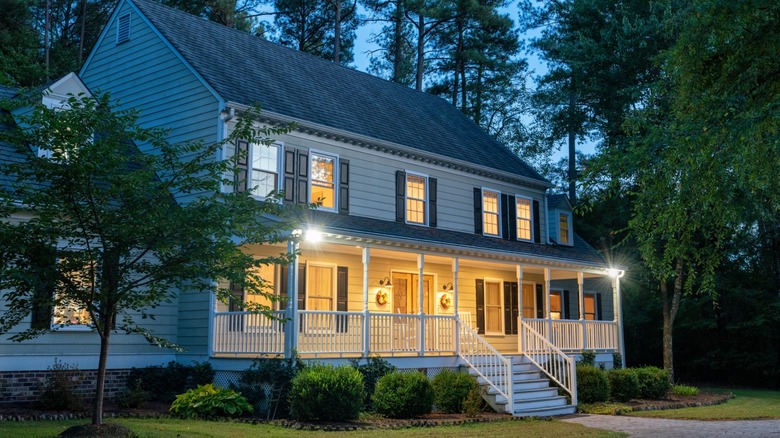 A colonial-style house at night with security lights.