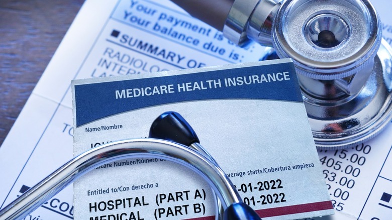 A Medicare insurance card on top of a medical bill with a stethoscope.