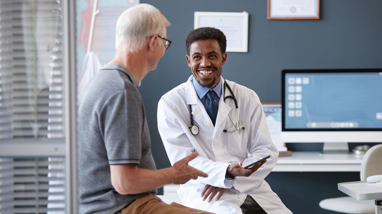 Older man speaking with a younger doctor on an examination table
