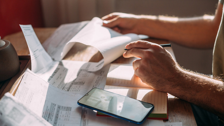 Close-up of a man's hands with a calculator and utility bills.