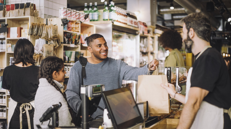 A smiling man paying for groceries at a grocery store.