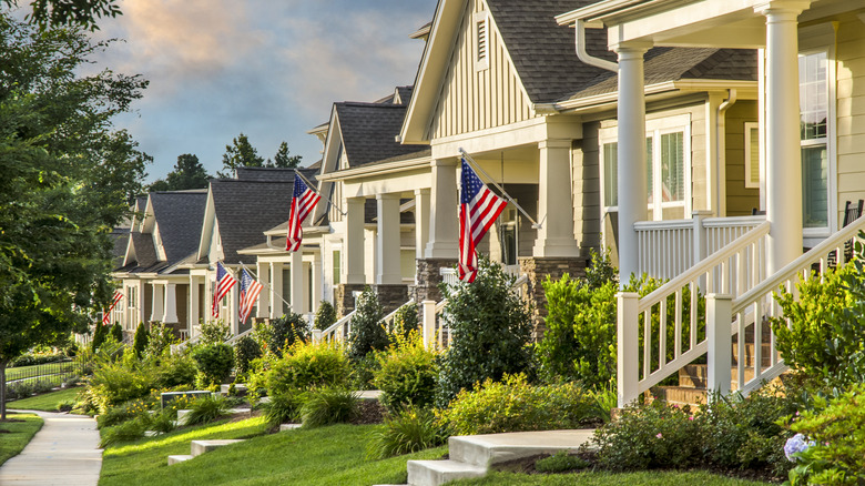 American Flags hang from the front of traditional, brick homes in an All-American suburb.