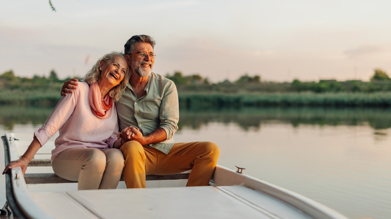 Senior couple laughing and holding hands while seated in a boat