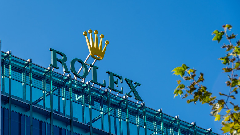 A closeup of the Rolex sign against a blue sky at the headquarters building.