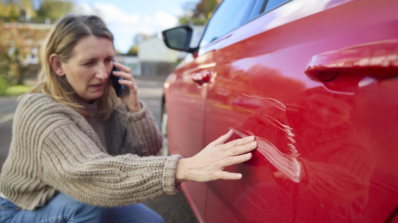 Woman inspecting damage to her red car