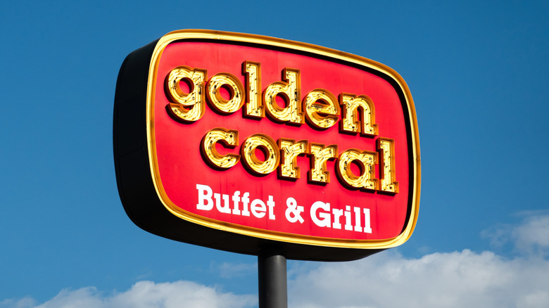 A bright yellow-and-gold Golden Corral buffet sign against a bright blue sky.