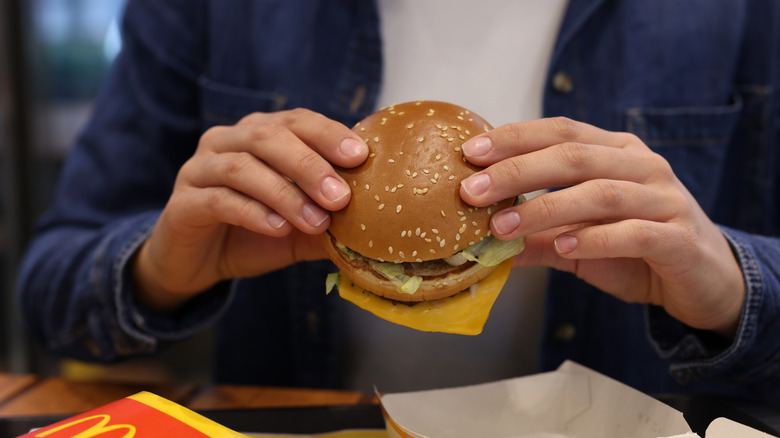 Person eating a cheeseburger and French fries from McDonald's