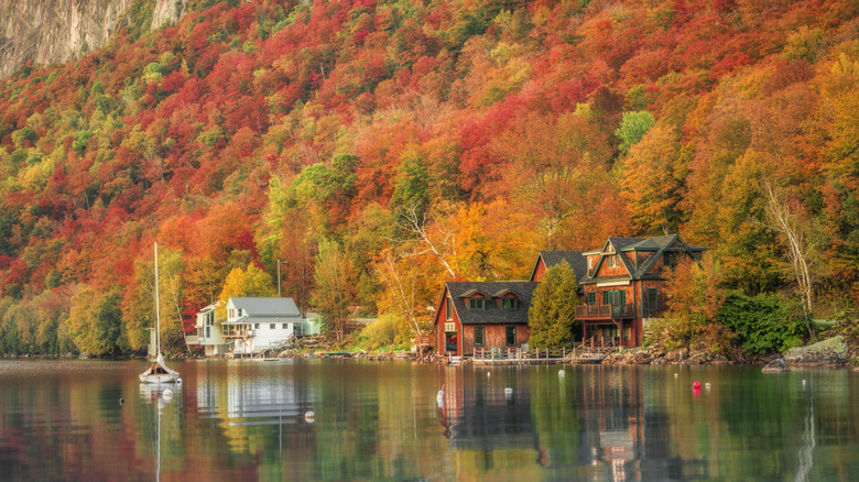 Autumn views of a lake, with two homes on the shore and an anchored sailboat, in Vermont