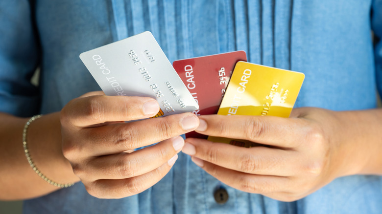 Close up of woman's hands holding three types of credit cards