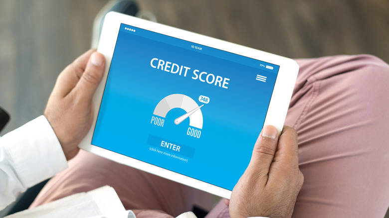 An over-the-shoulder shot of someone checking their credit score on a tablet