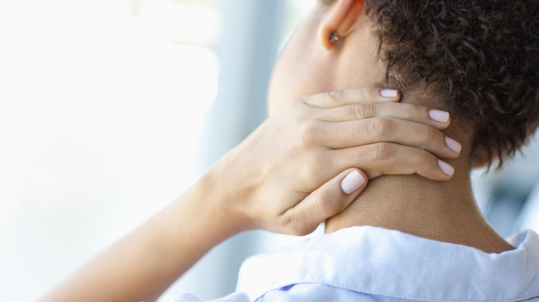 A hand with white painted fingernails clutches a neck, indicating neck tension