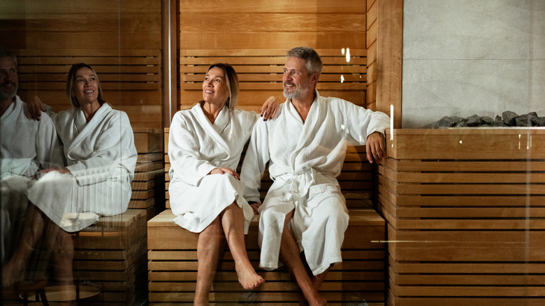 Happy couple wearing white bathrobes in a sauna